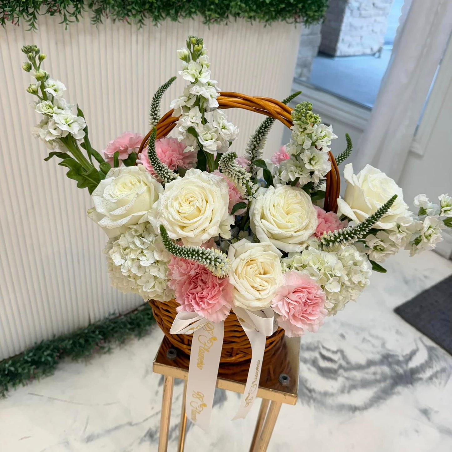 Blush and ivory roses, hydrangea and pink carnations in a sympathy flower basket