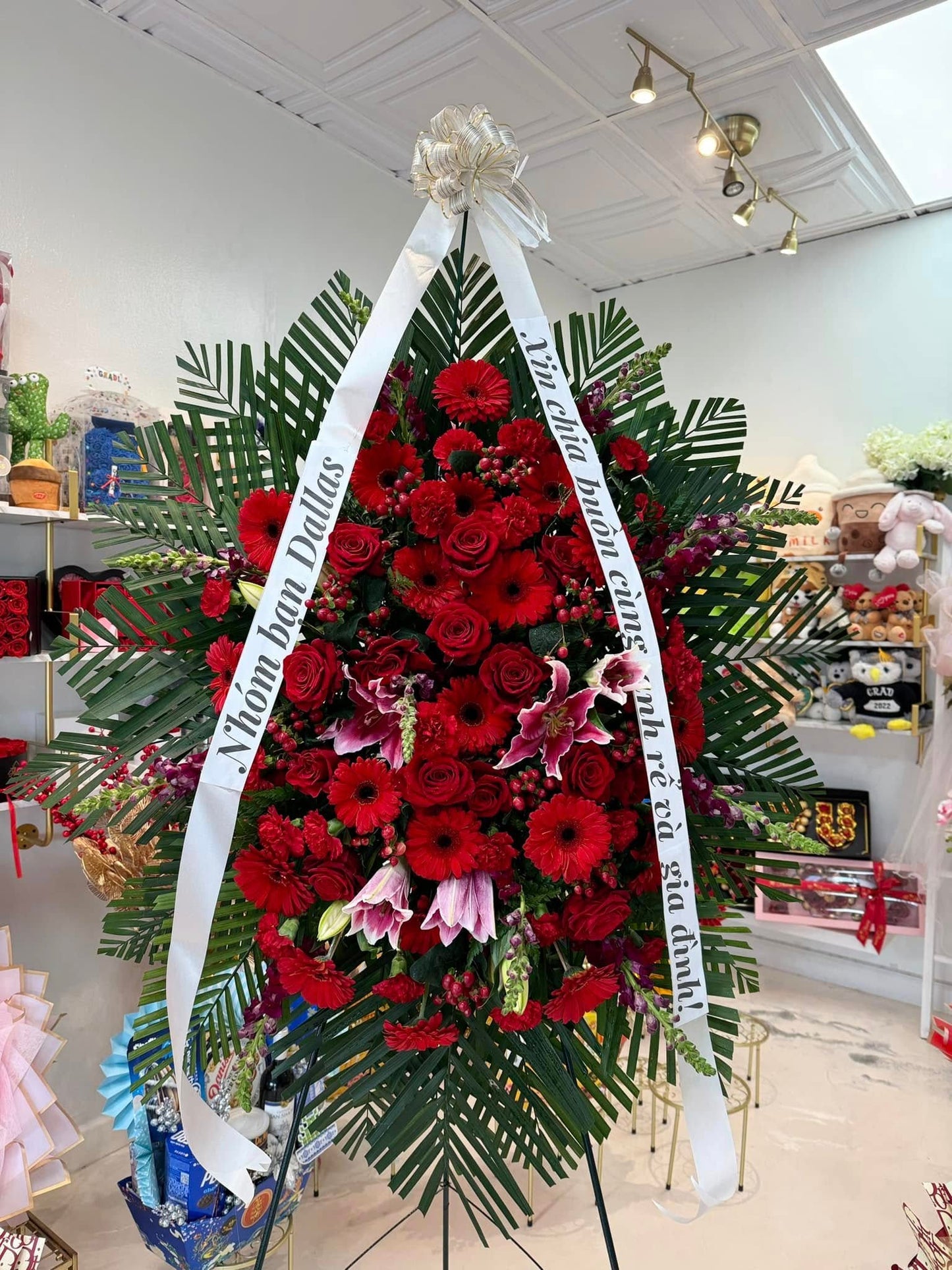 All-red sympathy standing spray with roses, gerberas, lilies and tropical greenery