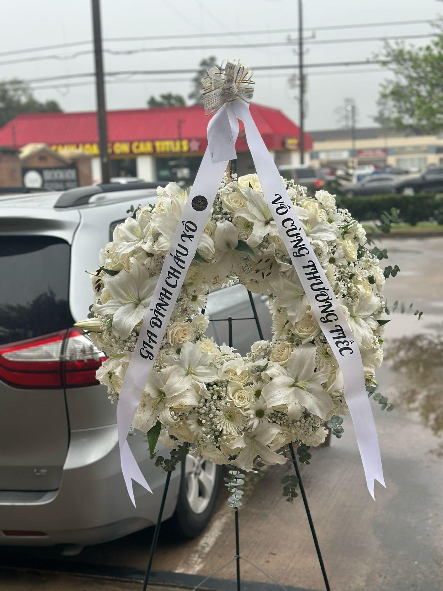 White lily and rose sympathy standing wreath with condolence ribbon