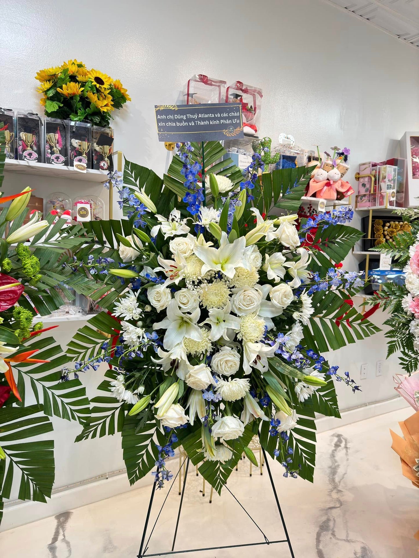 White and blue sympathy standing spray with lilies, roses and greenery