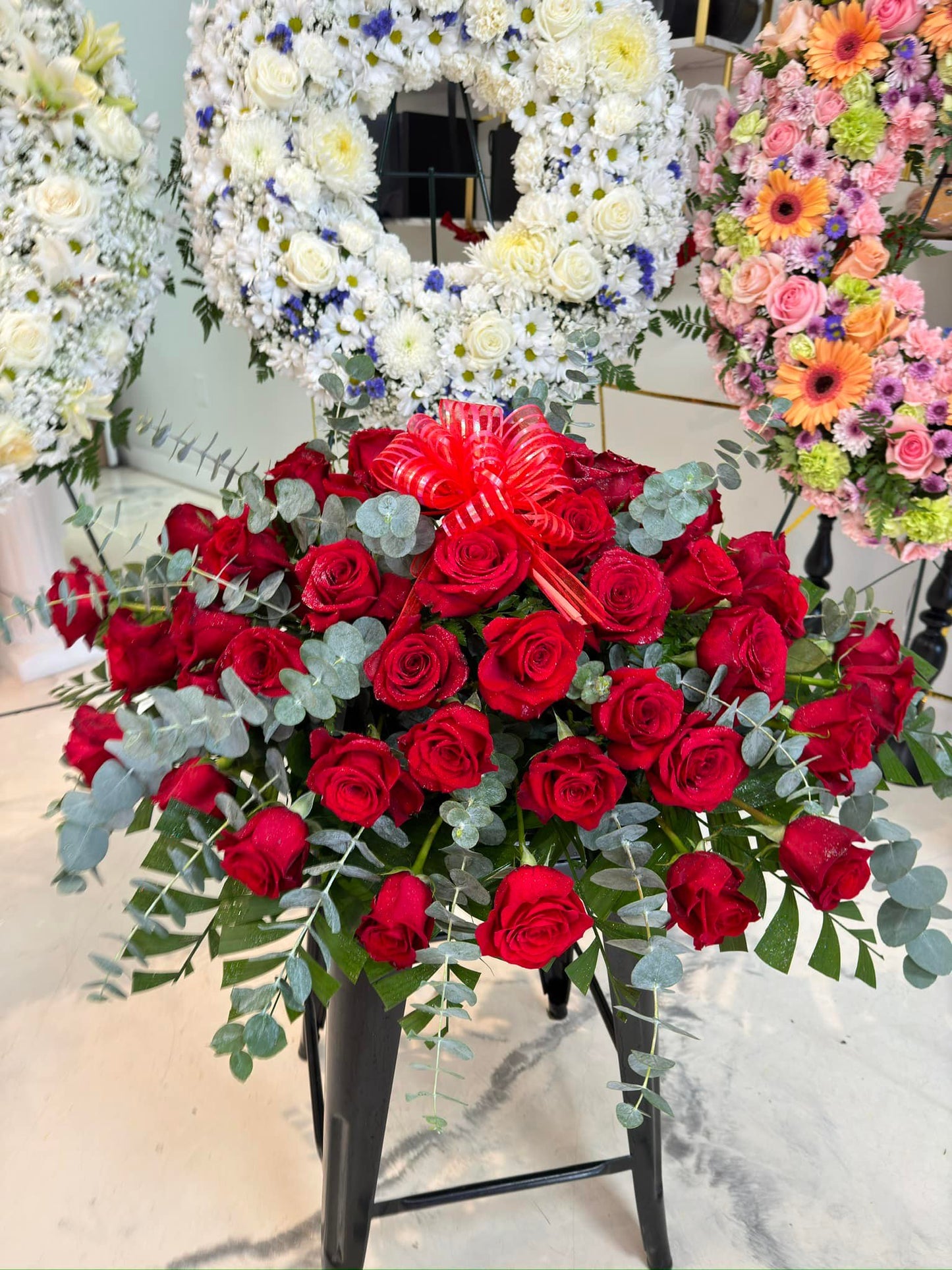 Vertical red rose funeral standing spray with eucalyptus greenery