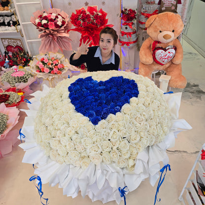 Giant bouquet of 365 roses with a royal-blue heart centered among ivory-white roses and layered white wrapping