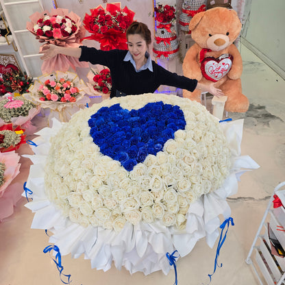 Giant bouquet of 365 roses with a royal-blue heart centered among ivory-white roses and layered white wrapping, alternate view 1