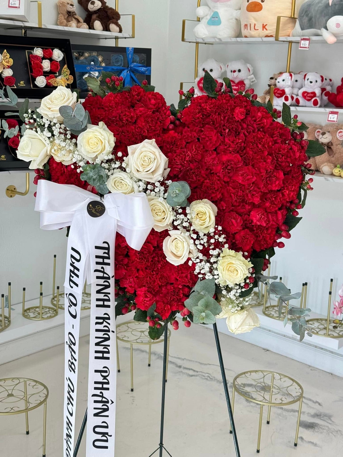 Red heart sympathy wreath with white roses and ribbon on a standing easel