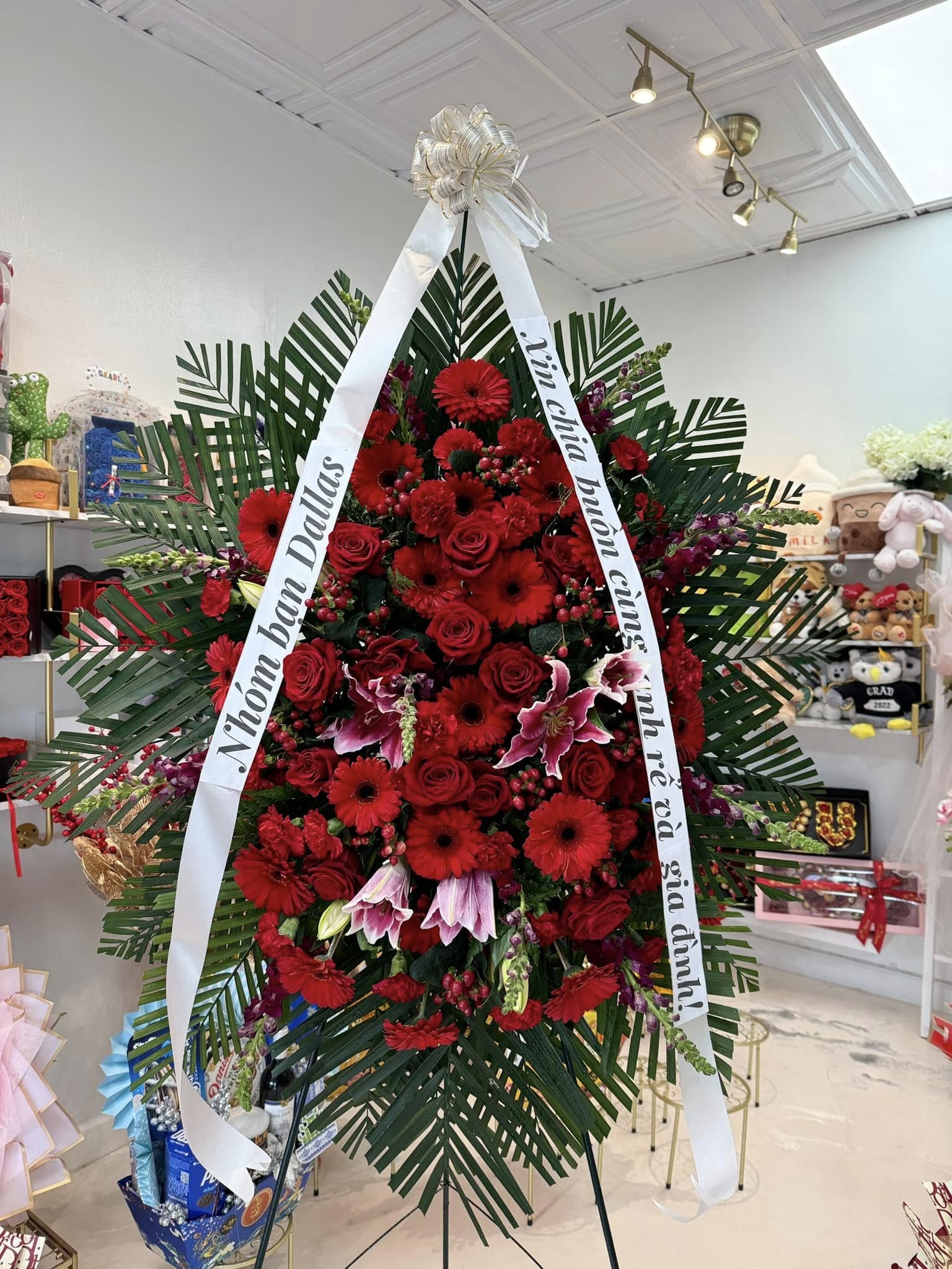 All-red sympathy standing spray with roses, gerberas, lilies and tropical greenery