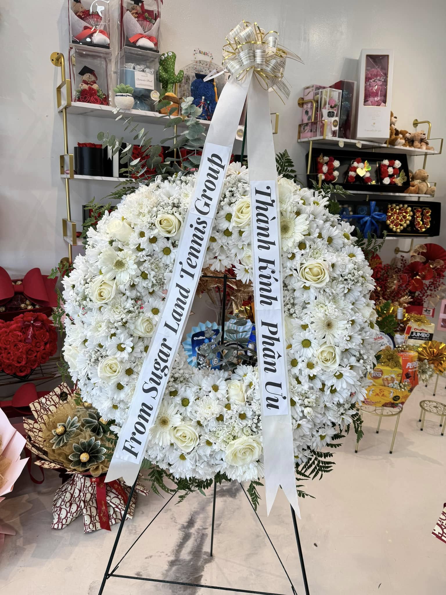 All-white sympathy standing wreath with roses and long condolence ribbon