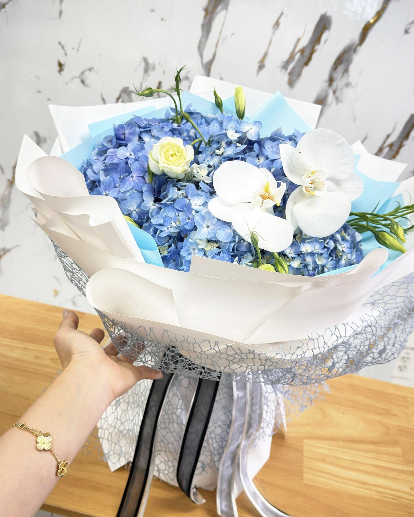Full blue hydrangea and white orchid bouquet in layered blue and white wrapping