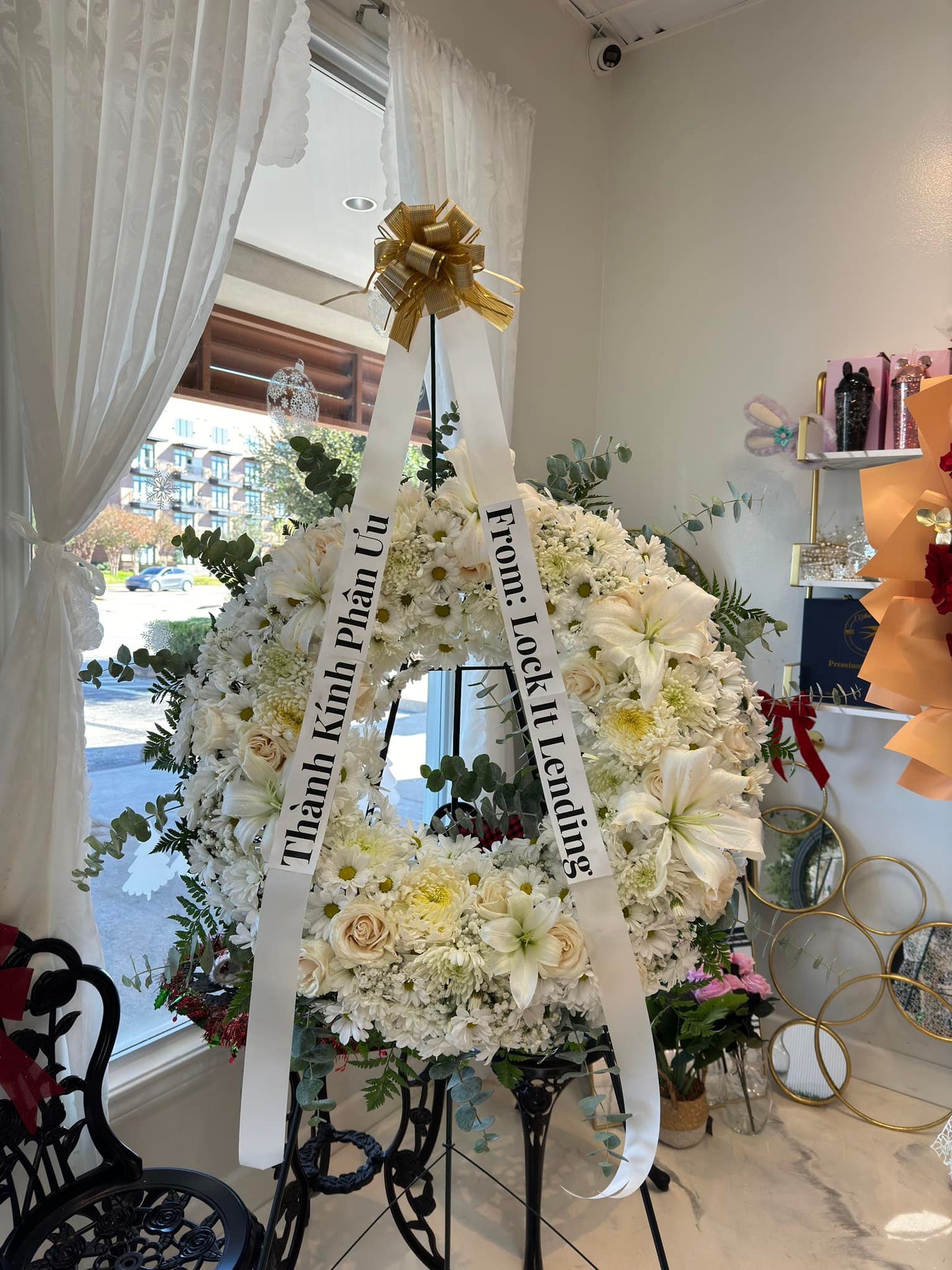 Elegant white garden sympathy wreath with roses, lilies and ribbon