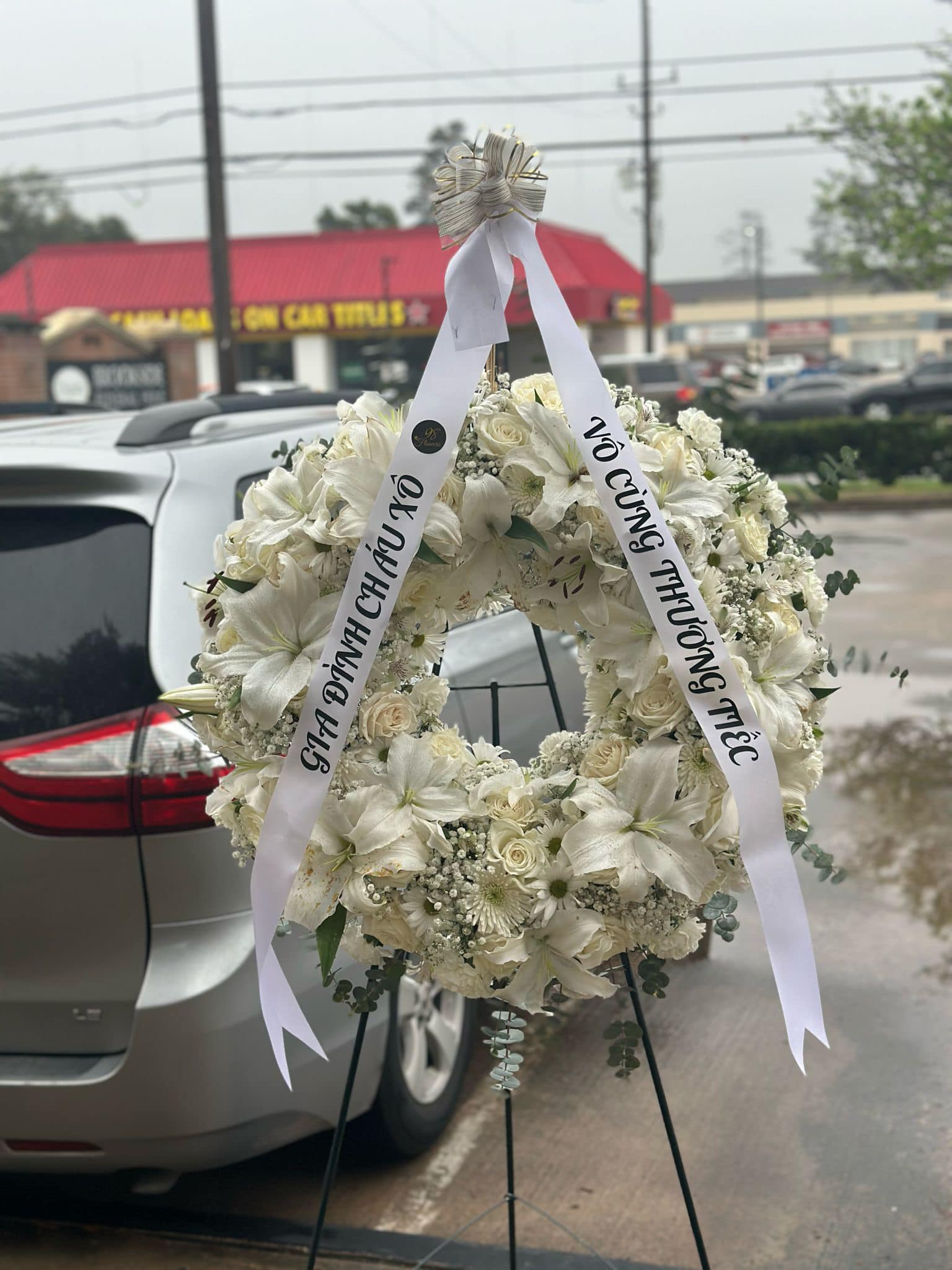 White lily and rose sympathy standing wreath with condolence ribbon