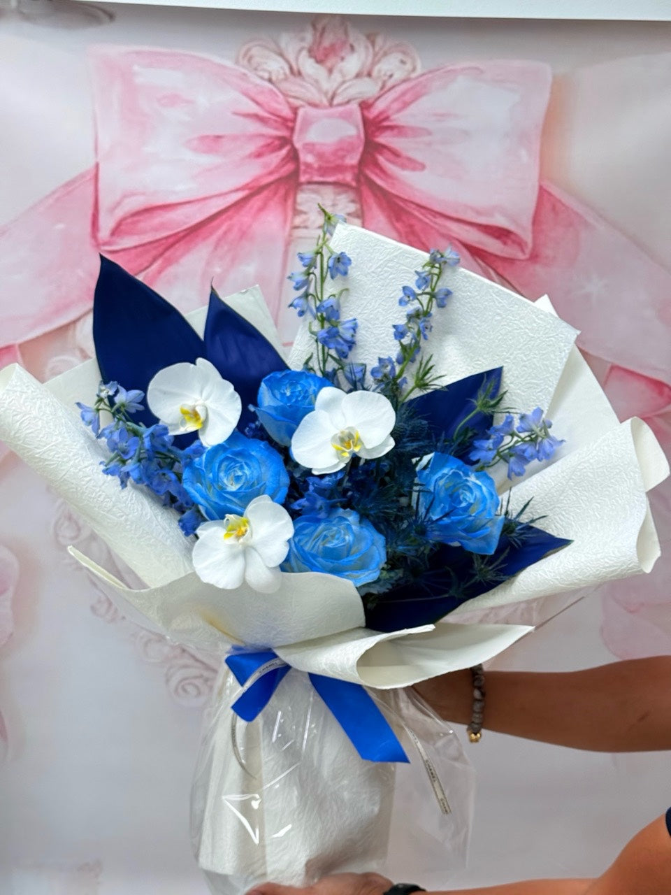 Full view of a blue rose and white orchid hand-tied bouquet