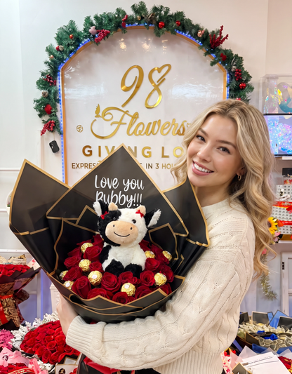 Woman holding 24 red roses with Ferrero Rocher chocolates, plush cow and custom topper