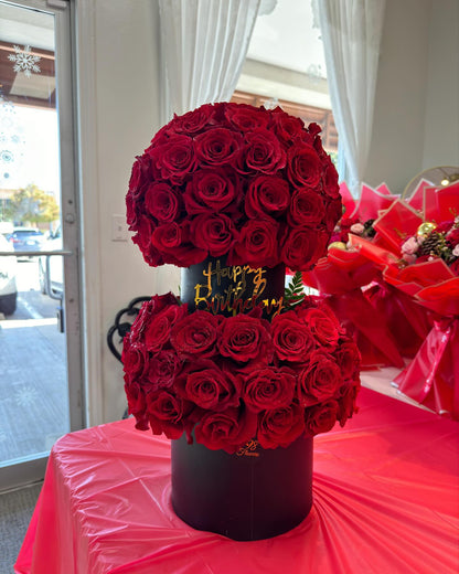 Two-tier tower of 150 red roses in black keepsake boxes with a gold birthday message