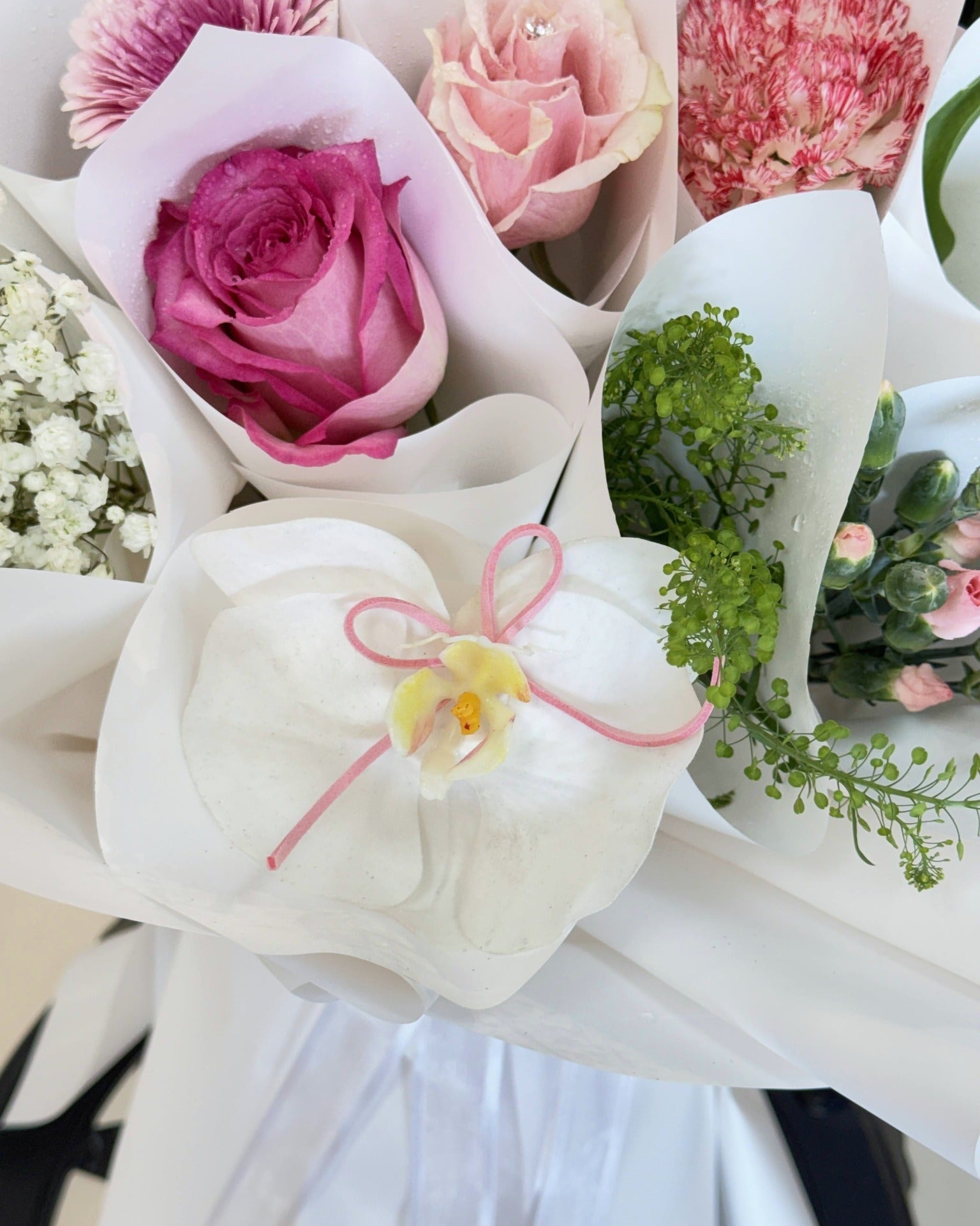 Close-up of white orchid, pink rose, and green accent mini bouquets