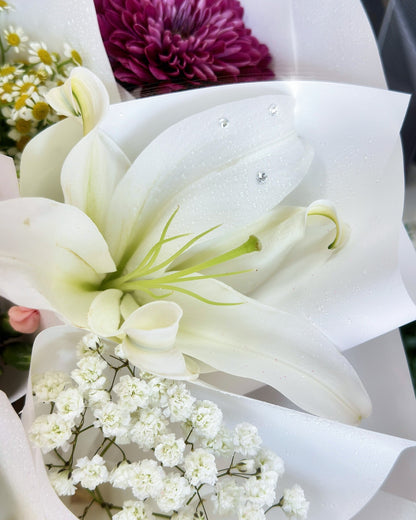 Close-up of white lilies, baby's breath, and peach roses in mini bouquets
