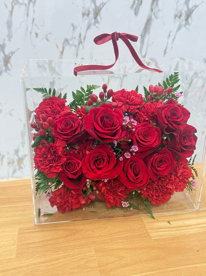 Fresh red roses and carnations in a clear acrylic flower box