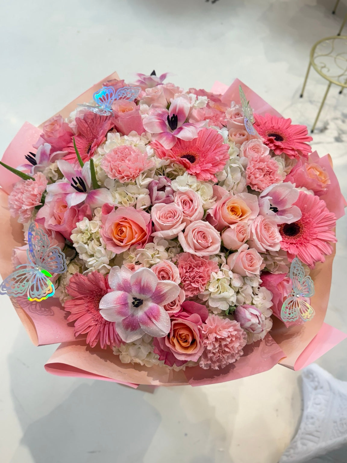 Angled view of a giant pink bouquet of fresh mixed flowers with butterfly accents