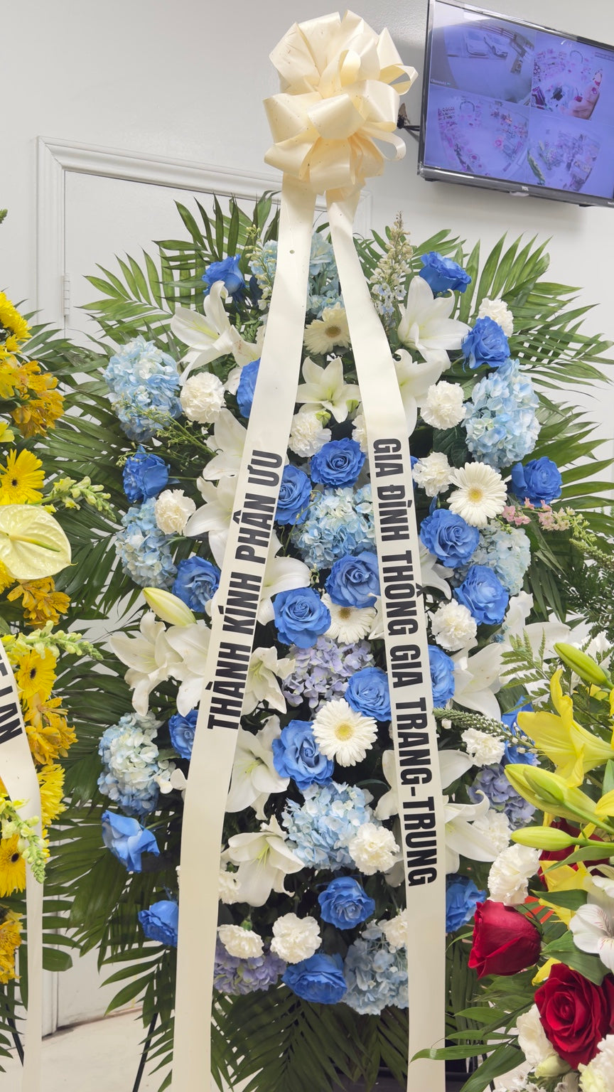Blue and white sympathy standing spray displayed with memorial ribbon