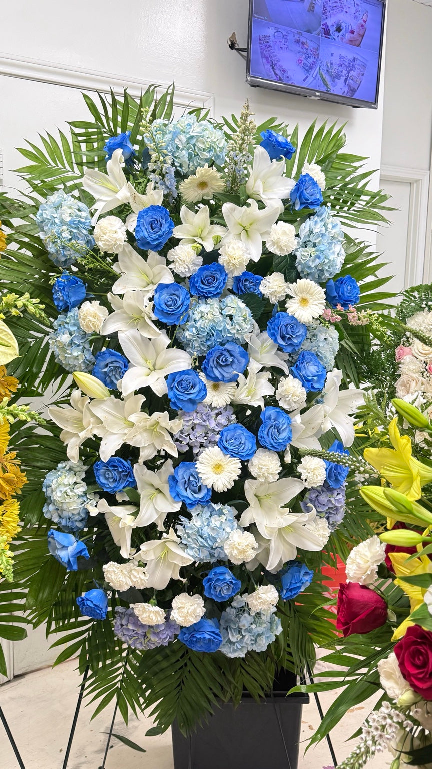 Grand blue and white sympathy standing spray with roses, lilies and hydrangeas