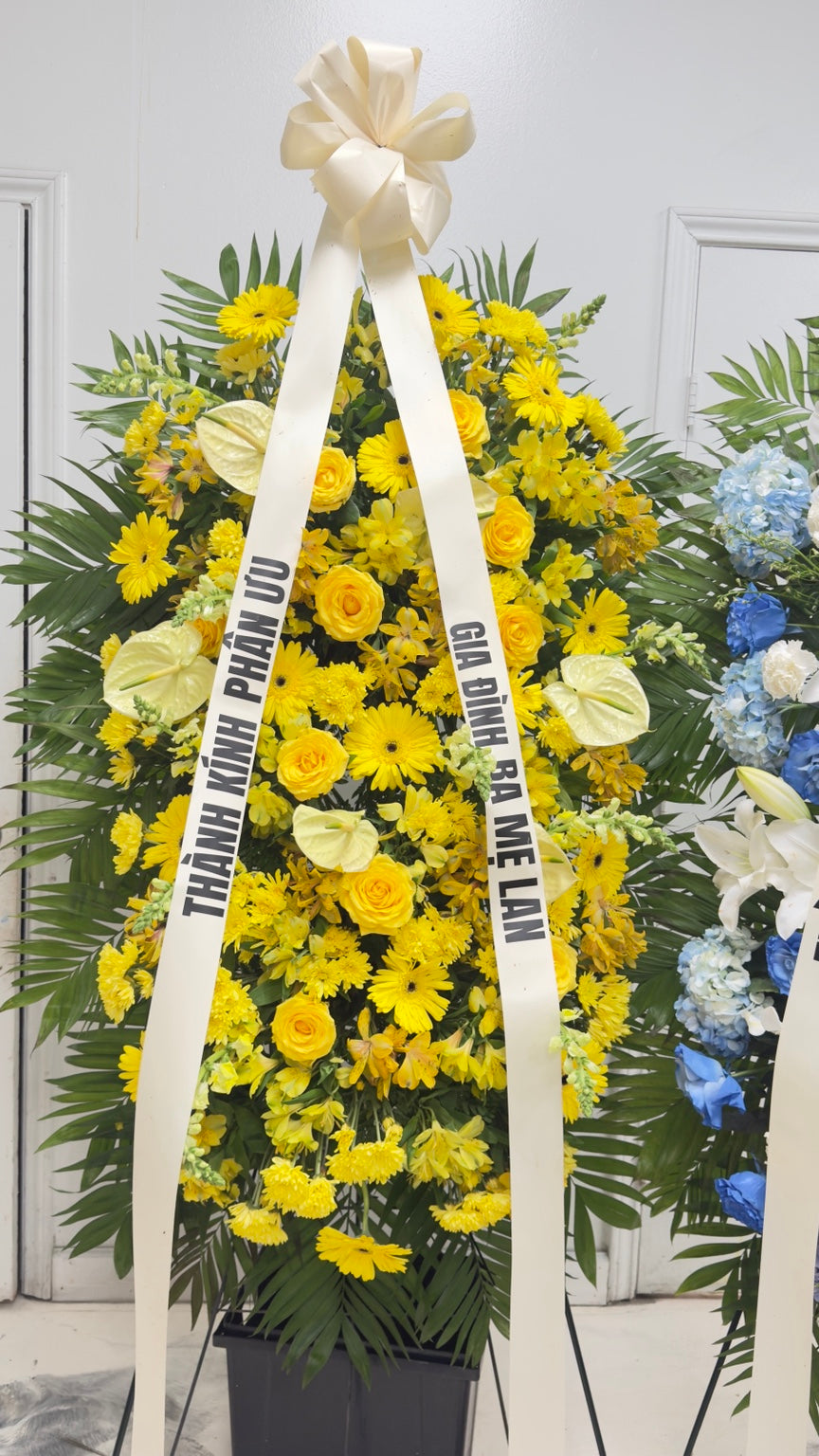 Yellow sympathy standing spray displayed with memorial ribbon