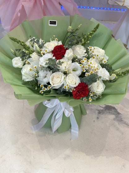 Round white rose bouquet with deep red accents, smaller white flowers, greenery, sage-green wrapping and a white bow