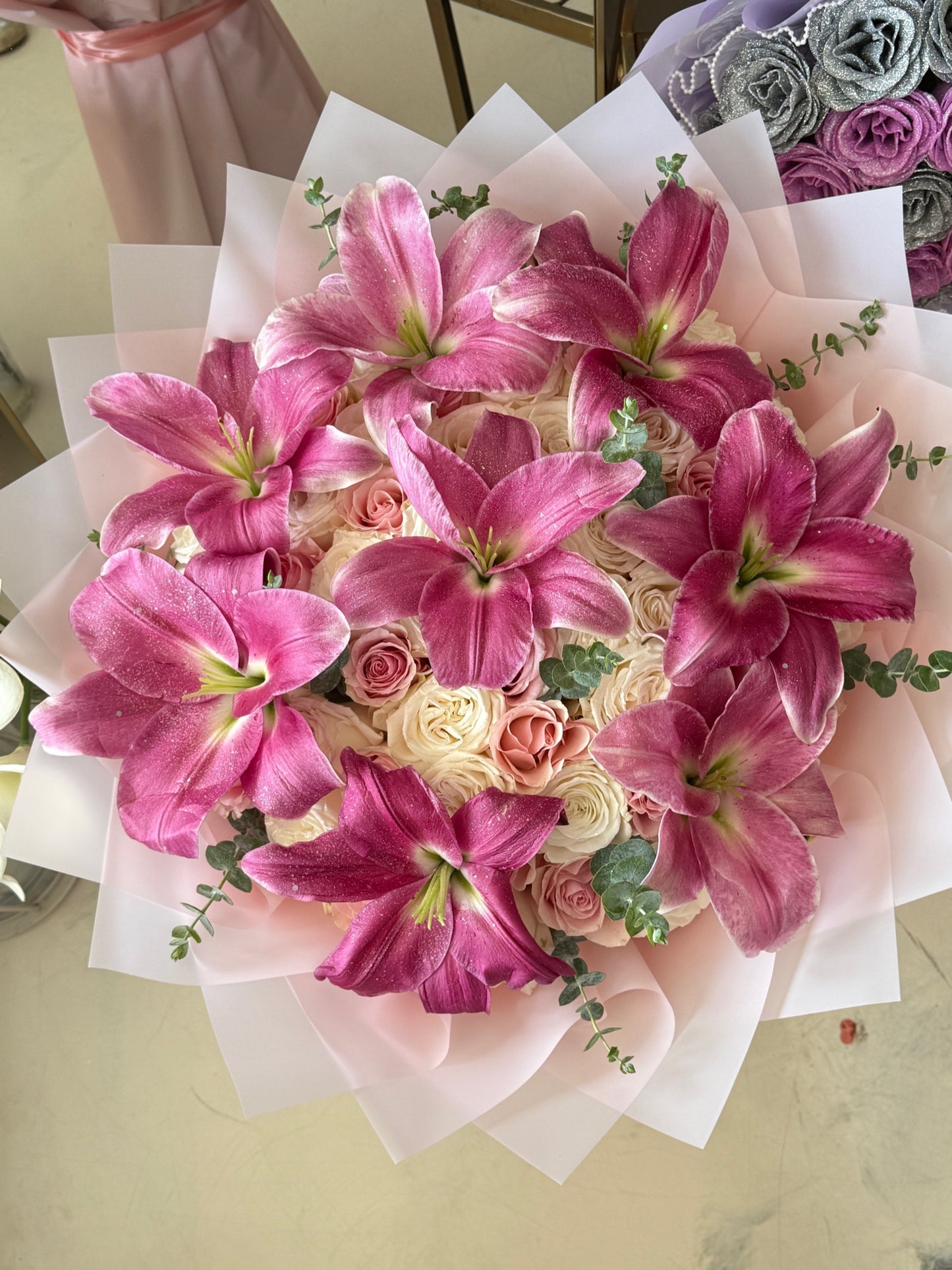 Close-up of pink lilies, pink and white roses, eucalyptus, and pale pink layered wrapping