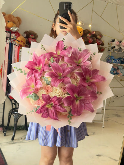 Woman holding a large bouquet of 50 pink and white roses with pink lilies and pale pink layered wrapping