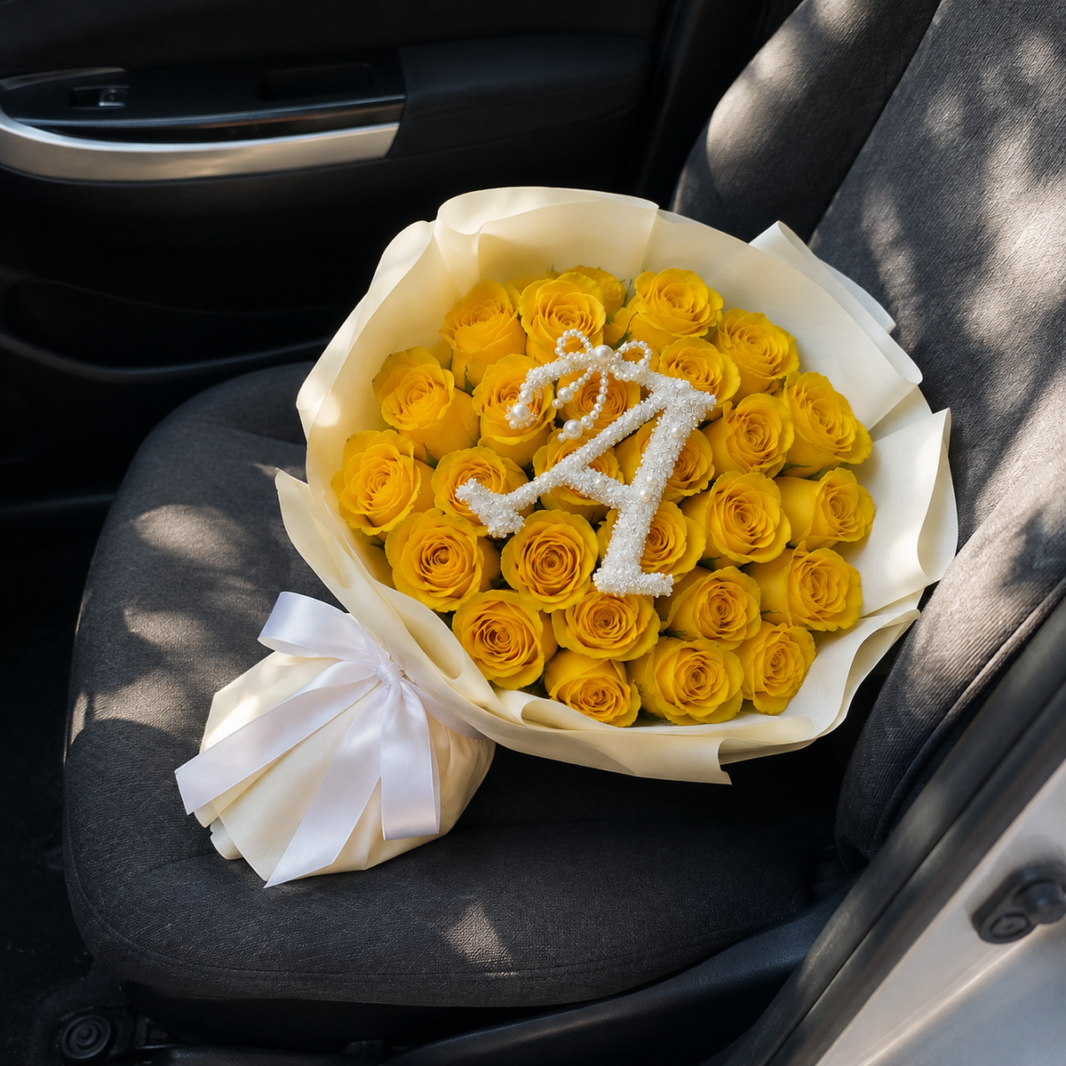 Sunlit Charm yellow rose bouquet with optional letter A resting on a car seat