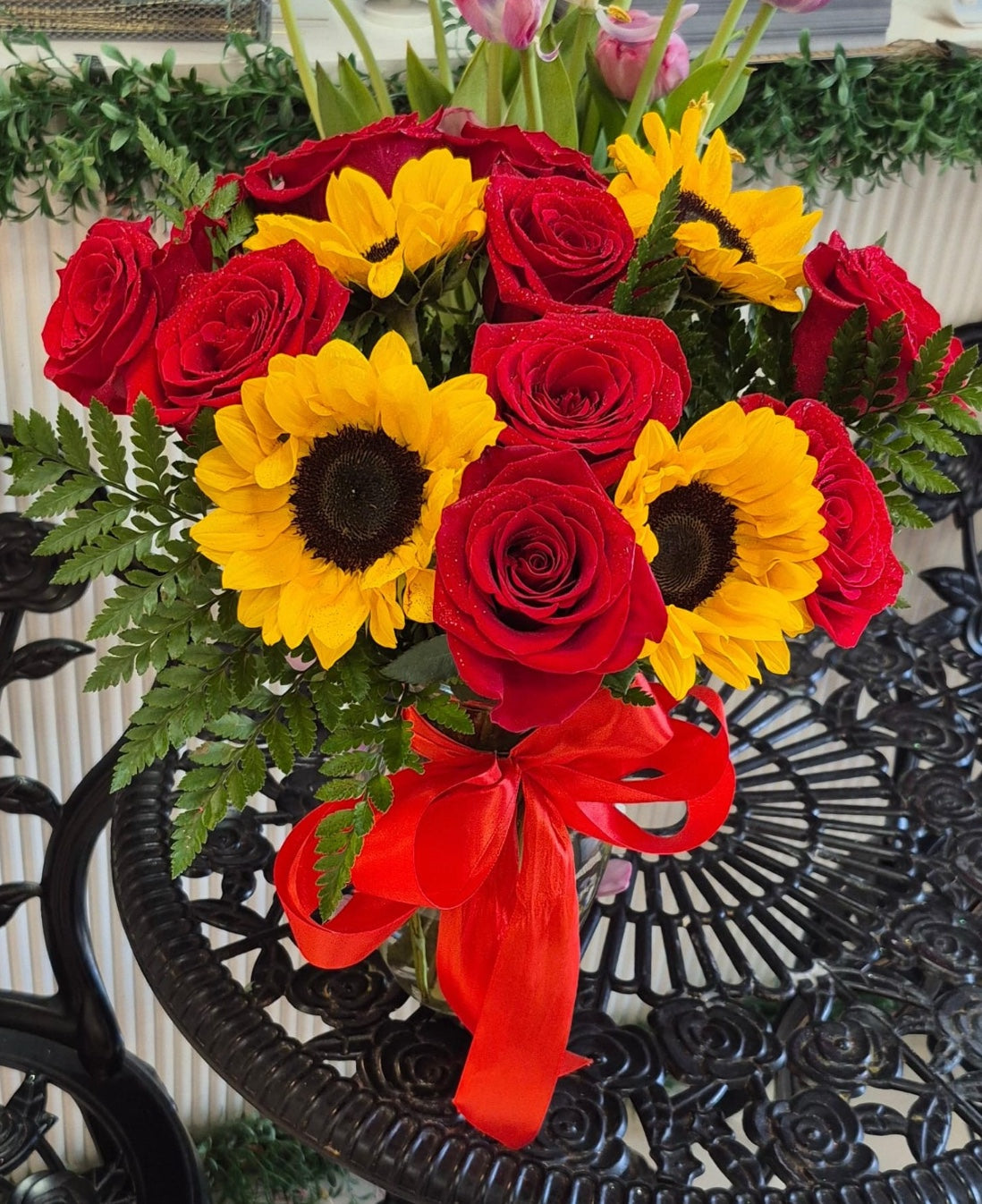 Sunlit Romance bouquet with red roses, yellow sunflowers, greenery, and red ribbon